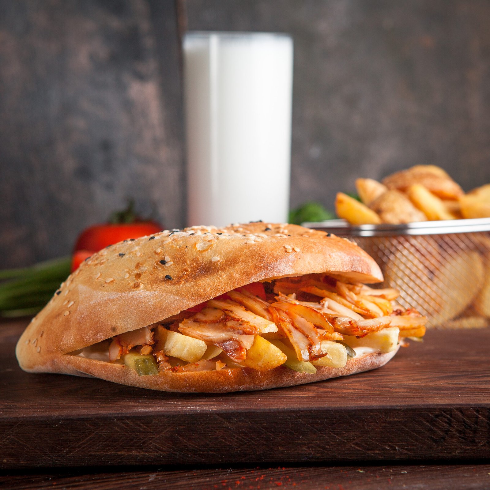 Side view doner with fried potatoes and ayran in board cookware on wooden background