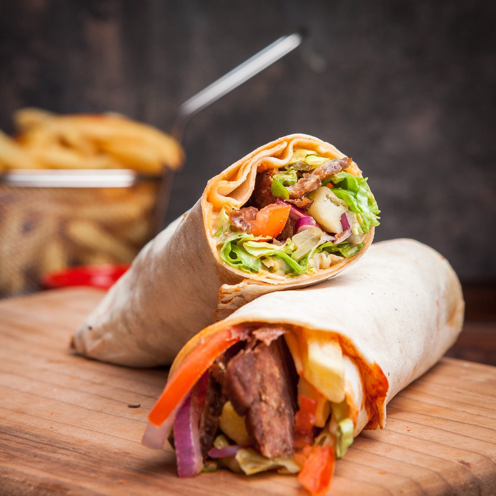 Side view shawarma with fried potatoes in board cookware on stone background